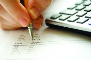  Person calculating finances using a calculator and pen on a paper document.